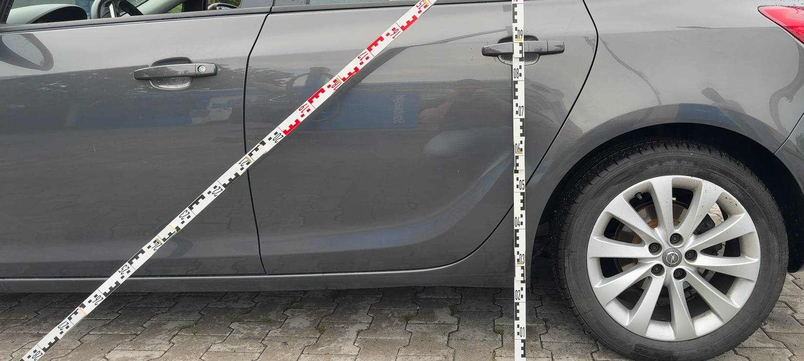 Oranger Fremdlack auf der dunklen Flanke eines Hyundai ix35, Beschädigung über beide Türen
